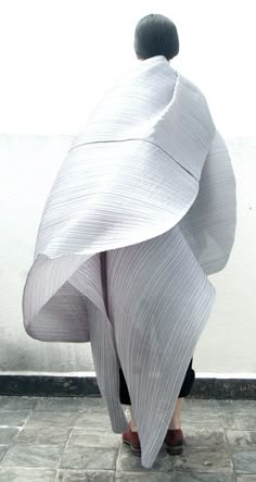 a person wrapped in a white blanket on top of a tiled floor next to a wall