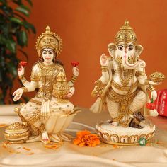 two statues of lord ganesh and goddess sit on a table