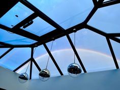 three disco balls hanging from the ceiling in a room with a skylight and rainbow