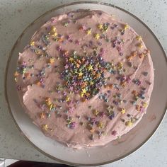 a cake with pink frosting and sprinkles on it sitting on a plate