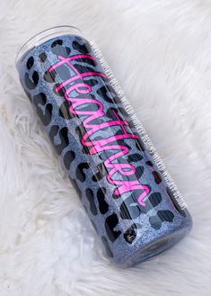 a black and pink hair brush sitting on top of a white fur covered floor next to a can