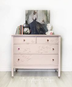 the dresser is painted pink and has an image on it, along with other items