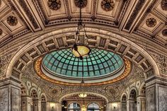 the inside of a building with an ornate ceiling and stained glass skylight above it