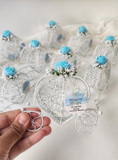 a hand holding a small white heart shaped box with blue flowers on it and several smaller hearts in the background