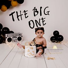 a baby sitting in front of a cake with the words the big one on it