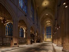 an empty cathedral with high ceilings and stained glass windows on the walls, along with stone flooring