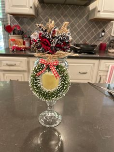 a glass vase filled with christmas decorations on top of a kitchen counter