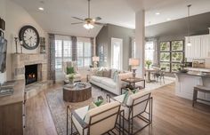 a living room filled with furniture and a fire place in front of a kitchen area