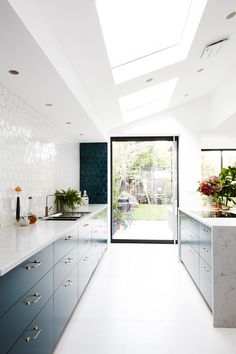 a kitchen with white counter tops and blue cabinets in front of a glass door that leads to an outside patio