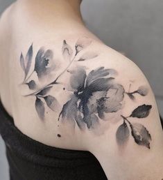 a black and white flower tattoo on the back of a woman's shoulder,