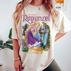 a woman wearing a rapunzel t - shirt in front of a potted plant