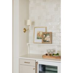 a kitchen with white tile and gold trim on the wall above it is an art piece