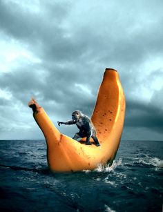 a man riding on the back of an orange banana in the middle of the ocean