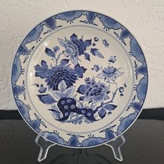 a blue and white plate sitting on top of a metal stand next to a wall