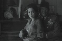 an old black and white photo of a man in uniform next to a young woman