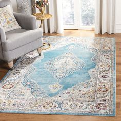 a blue area rug with an ornate design on the center in front of a chair