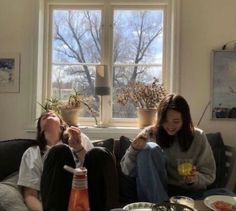 two women sitting on a couch with drinks in their hands