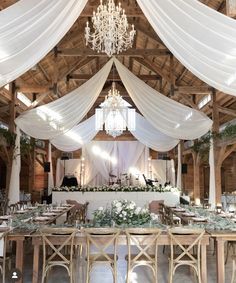 an indoor wedding venue with white draping and chandelier hanging from the ceiling