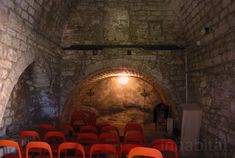 an old brick tunnel with rows of red chairs in front of it and a light at the end