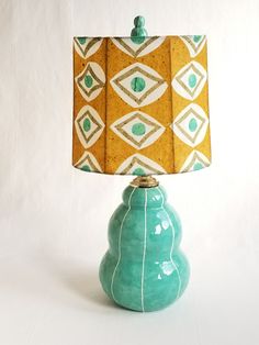 a lamp that is sitting on top of a white surface with a blue base and yellow lampshade