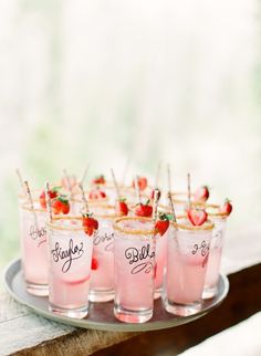 small glasses with strawberries and lemons are on a tray, ready to be served