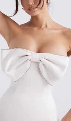 a woman wearing a white dress with a big bow