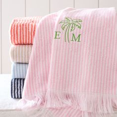 towels with palm trees and monogramming on them are lined up next to each other