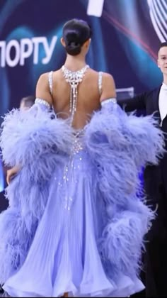 the back of a woman's dress with feathers on it, and two men in tuxedos