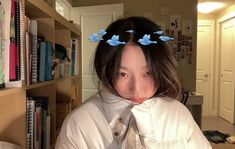 a woman with blue butterflies on her head in front of bookshelves and a bookcase