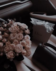 a bouquet of pink roses sitting on the dashboard of a car next to a purse