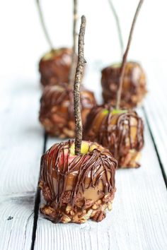 four pieces of chocolate covered apple sitting on top of a white wooden table next to each other