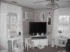 black and white photograph of living room with tv, couches, chairs and windows