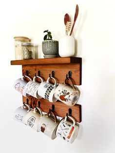 a wooden shelf with coffee cups and spoons hanging from it's hooks on the wall