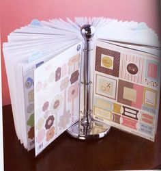 an open binder with scrapbook pages attached to it on a table next to a pink wall