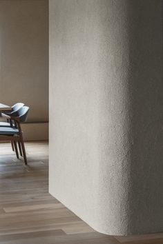 an empty room with a table and chairs next to a tall column in the center