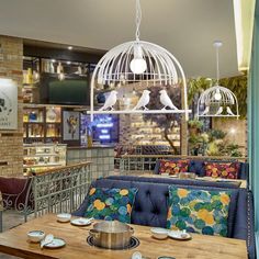 the interior of a restaurant with blue couches and birdcages