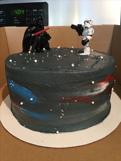 a star wars themed birthday cake with two figures on top and frosting sprinkles