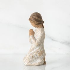 a ceramic figurine of a woman sitting on her knees with her hands clasped