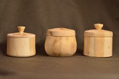 three wooden containers with lids on a brown background