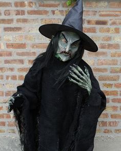 a man dressed as a witch standing in front of a brick wall