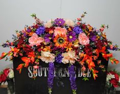 an arrangement of colorful flowers in a black box with the word south end painted on it