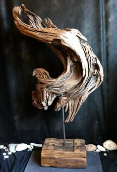 a wooden sculpture sitting on top of a table next to a black cloth covered wall