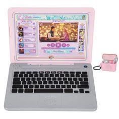 an open laptop computer sitting on top of a white table next to a pink camera