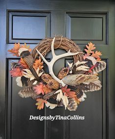 a wreath with antlers, leaves and pine cones on the front door for fall