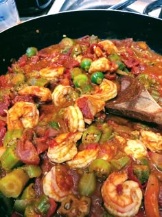 a skillet filled with shrimp and vegetables on top of a stove