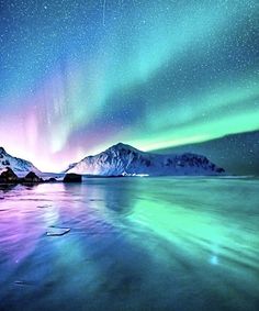 the aurora bore is shining brightly in the night sky over water and snow covered mountains