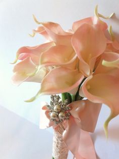 a bouquet of pink flowers in a vase on a white tablecloth with ribbon and beading