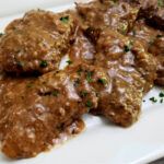 some meat with gravy on a plate and garnished with parsley