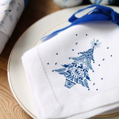 a white plate topped with a napkin covered in blue and white christmas tree designs on it