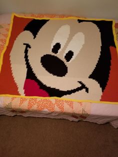 a close up of a pillow on a bed with a mickey mouse face drawn on it